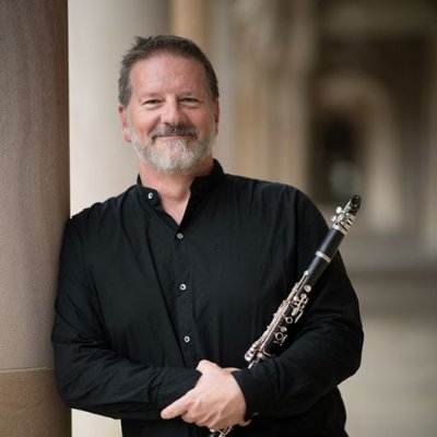 A man standing in a sandstone building holding a clarinet